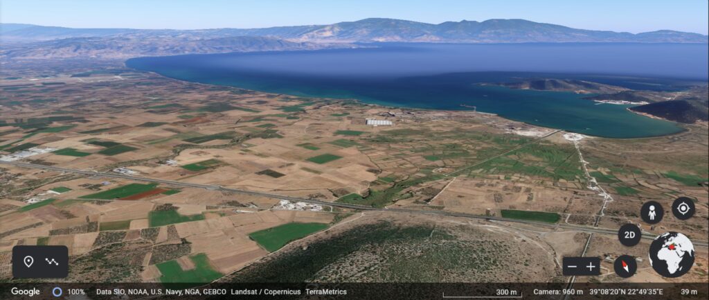 A Google Earth generated image overlooking the Almyros plain and the Pagasitic gulf to the northeast with the city of Volos in the centre on the other side of the gulf and the acropolis of Hellenistic Halos at the bottom. The Voulokaliva is located adjacent to the highway; Magoula Plataniotiki is located closer to the coast